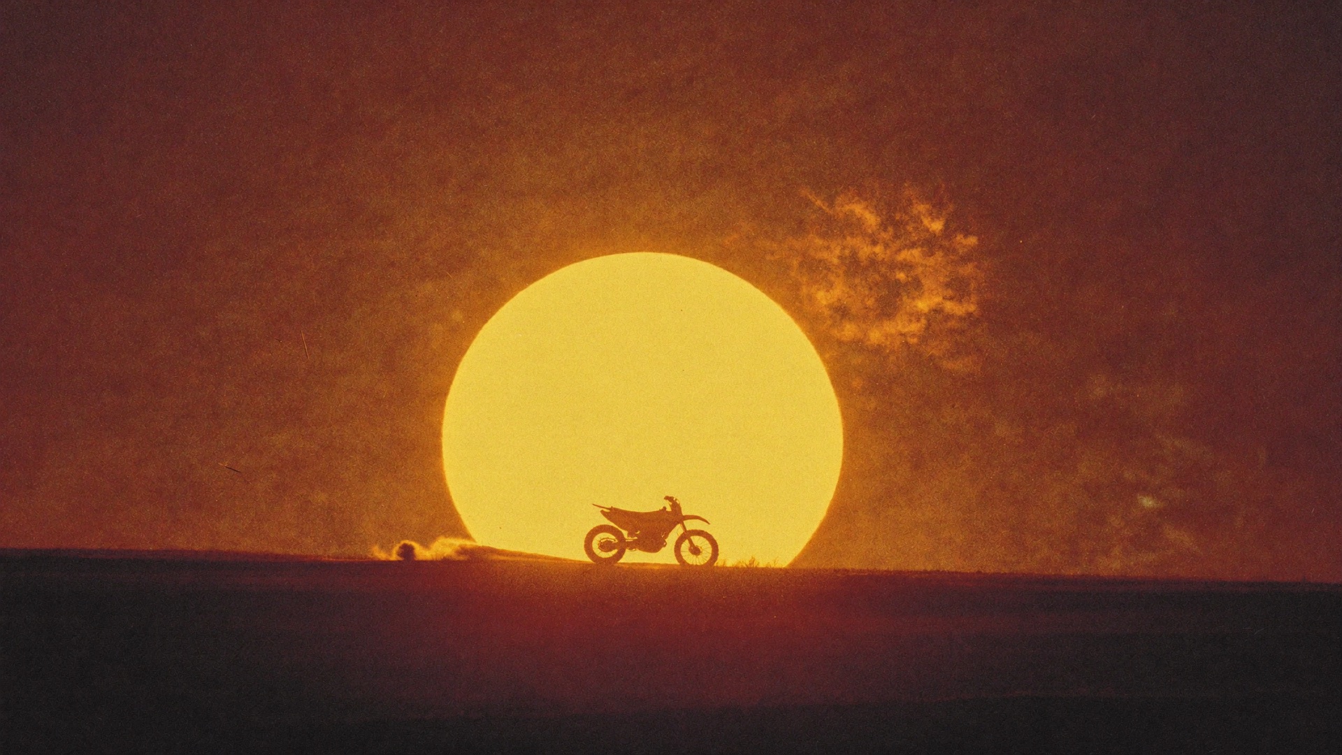 Dirt bike silhouetted against a colossal setting sun
